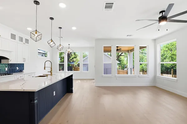 a large kitchen with kitchen island granite countertop a stove a sink a large window and wooden floor