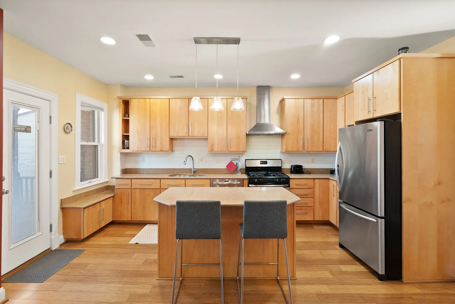 a kitchen with stainless steel appliances granite countertop a table chairs sink refrigerator and cabinets