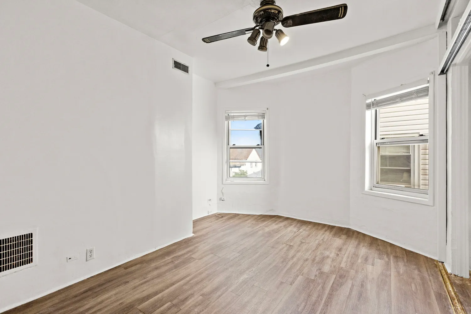 a view of empty room with wooden floor and fan