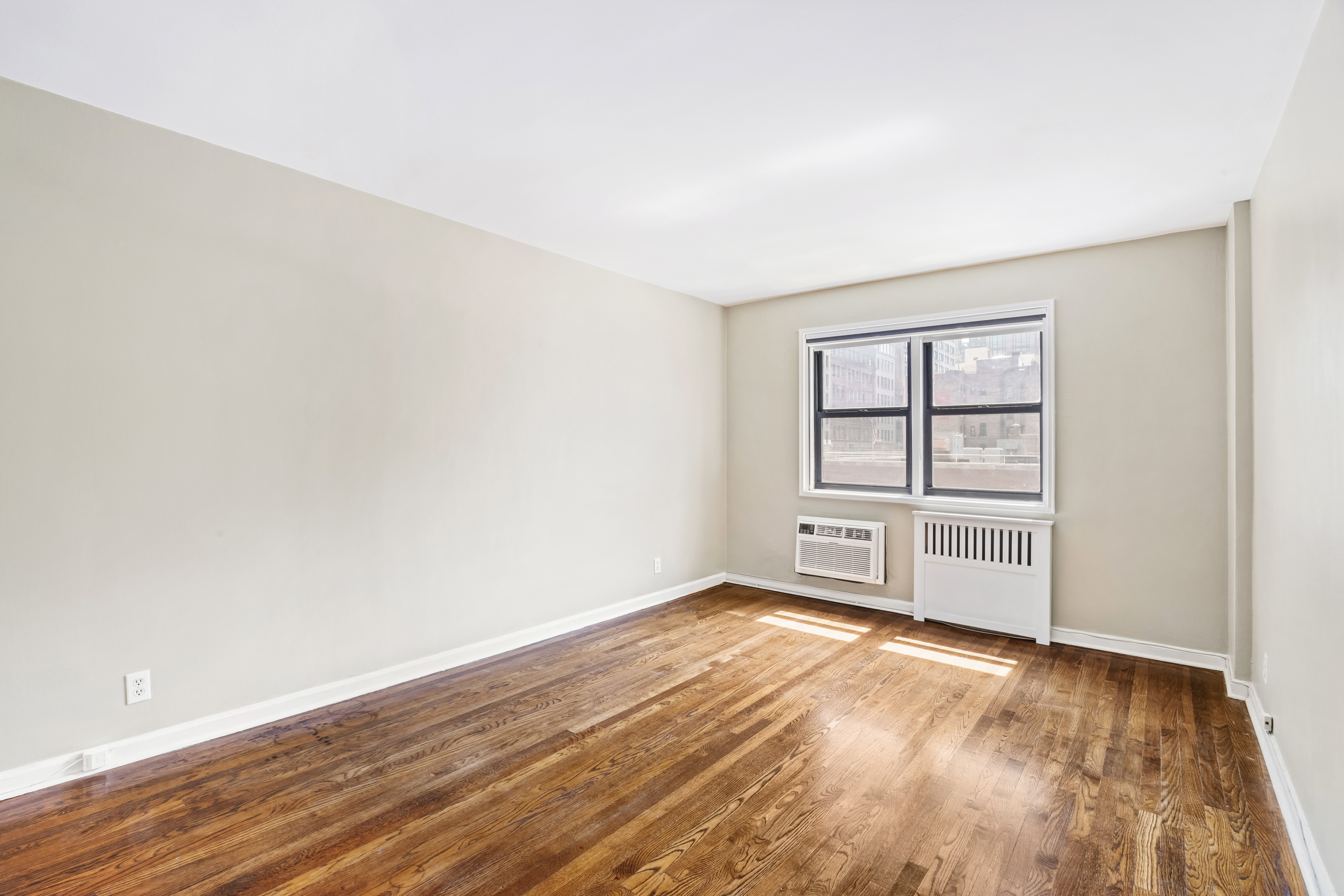 140 7th Avenue, Unit 4J Manhattan, NY 10011 - Photo 6 of 8 an empty room with wooden floor cabinet and windows