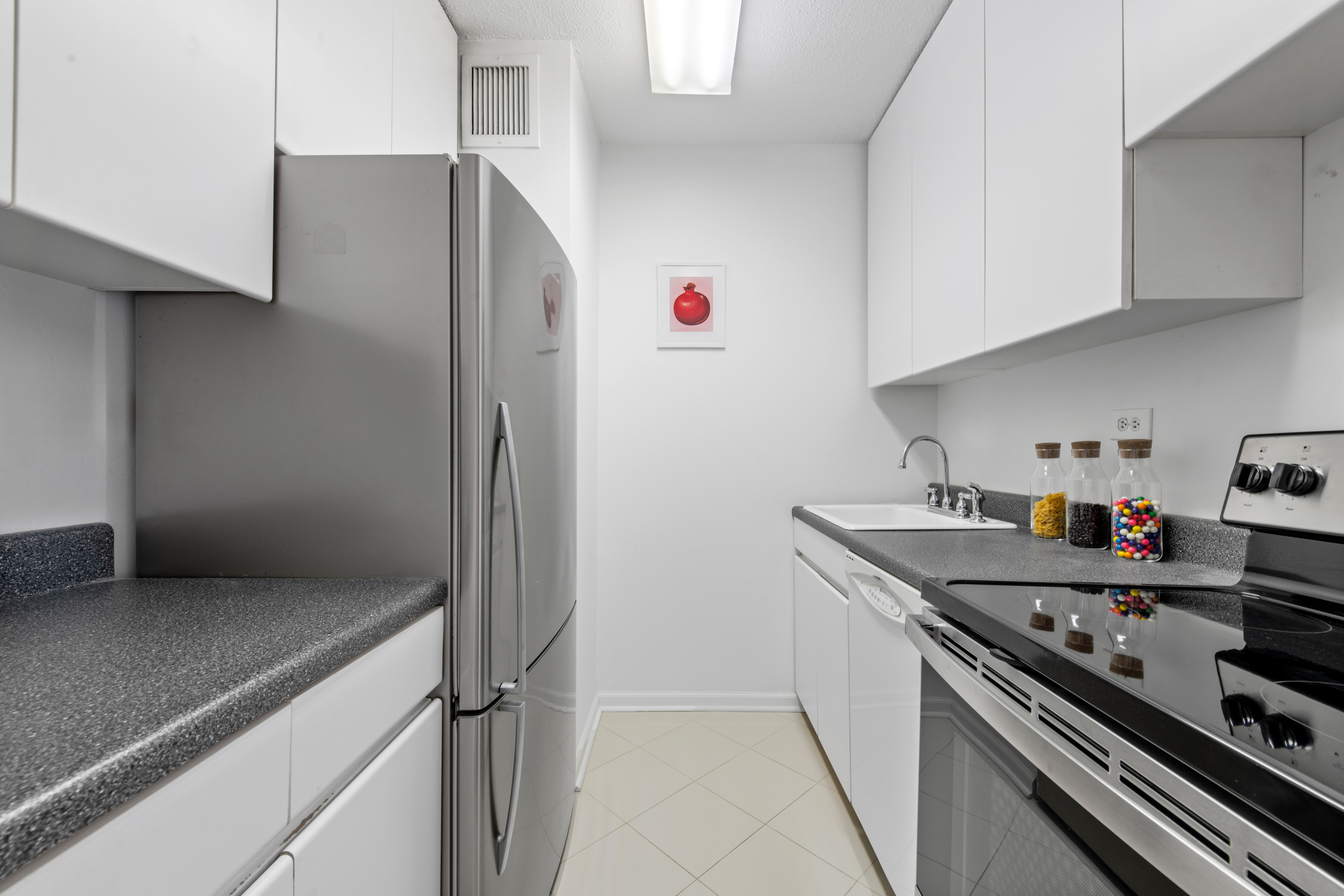 300 East 54th Street, Unit 23J Manhattan, NY 10022 - Photo 5 of 18 a kitchen with stainless steel appliances granite countertop a sink and a refrigerator