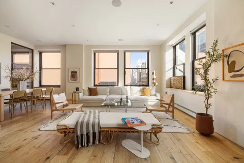 a living room with furniture two window and wooden floor