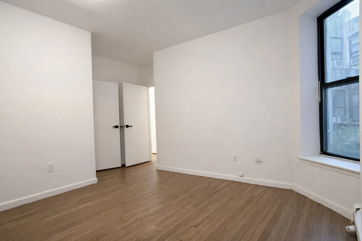 an empty room with wooden floor and a window