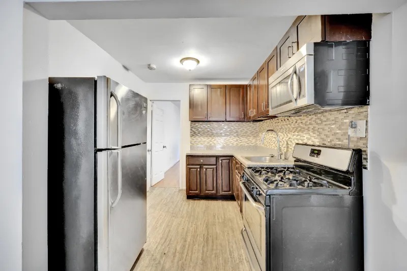 255 Covert Street Brooklyn, NY 11207 - Photo 12 of 18 a kitchen with stainless steel appliances granite countertop a refrigerator and a stove top oven