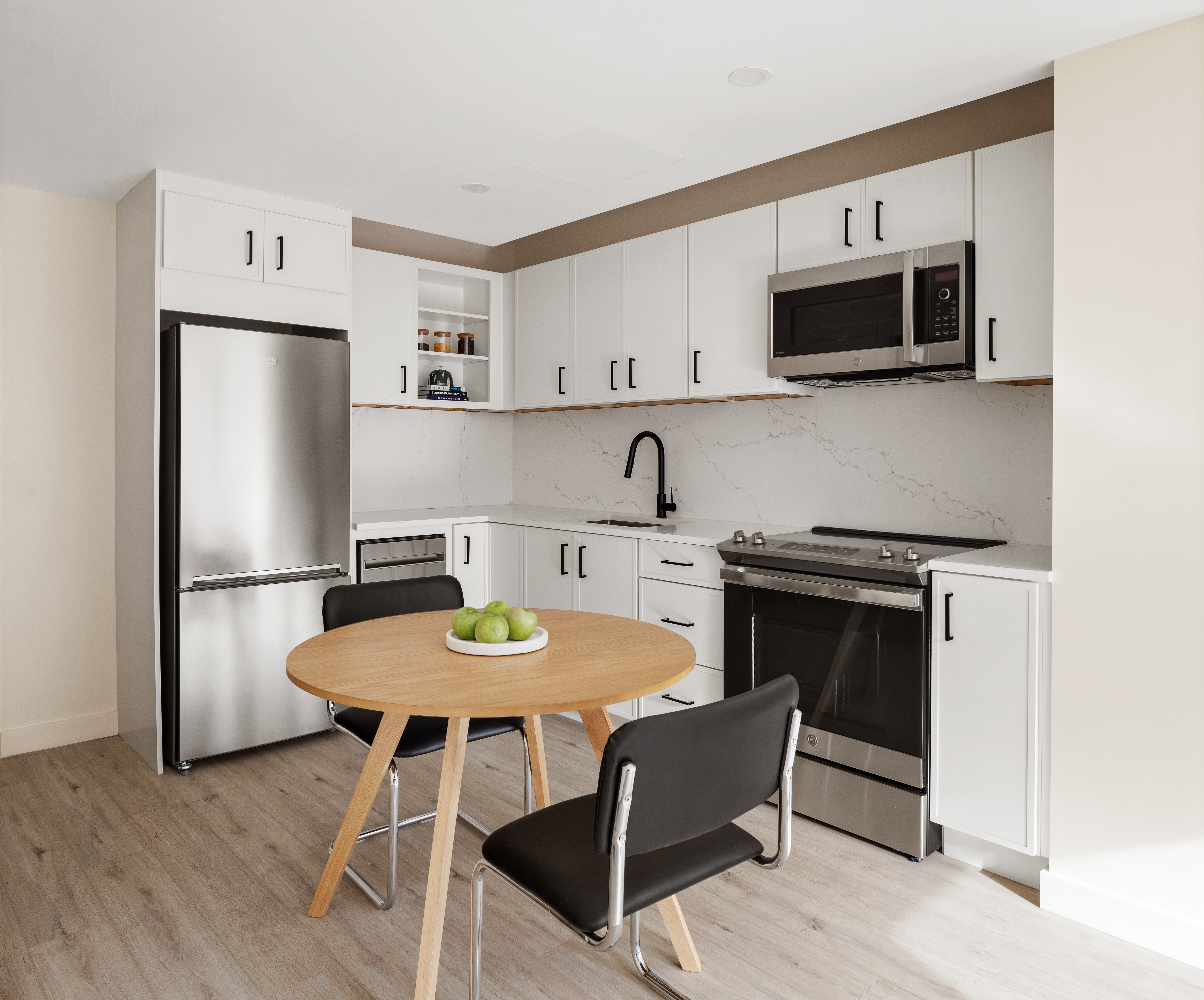 130 East 177th Street, Unit 9B Bronx, NY 10453 - Photo 7 of 18 a kitchen with stainless steel appliances a dining table chairs microwave and refrigerator