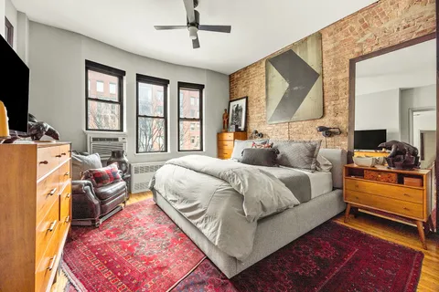 a spacious bedroom with a bed a flat screen tv and windows