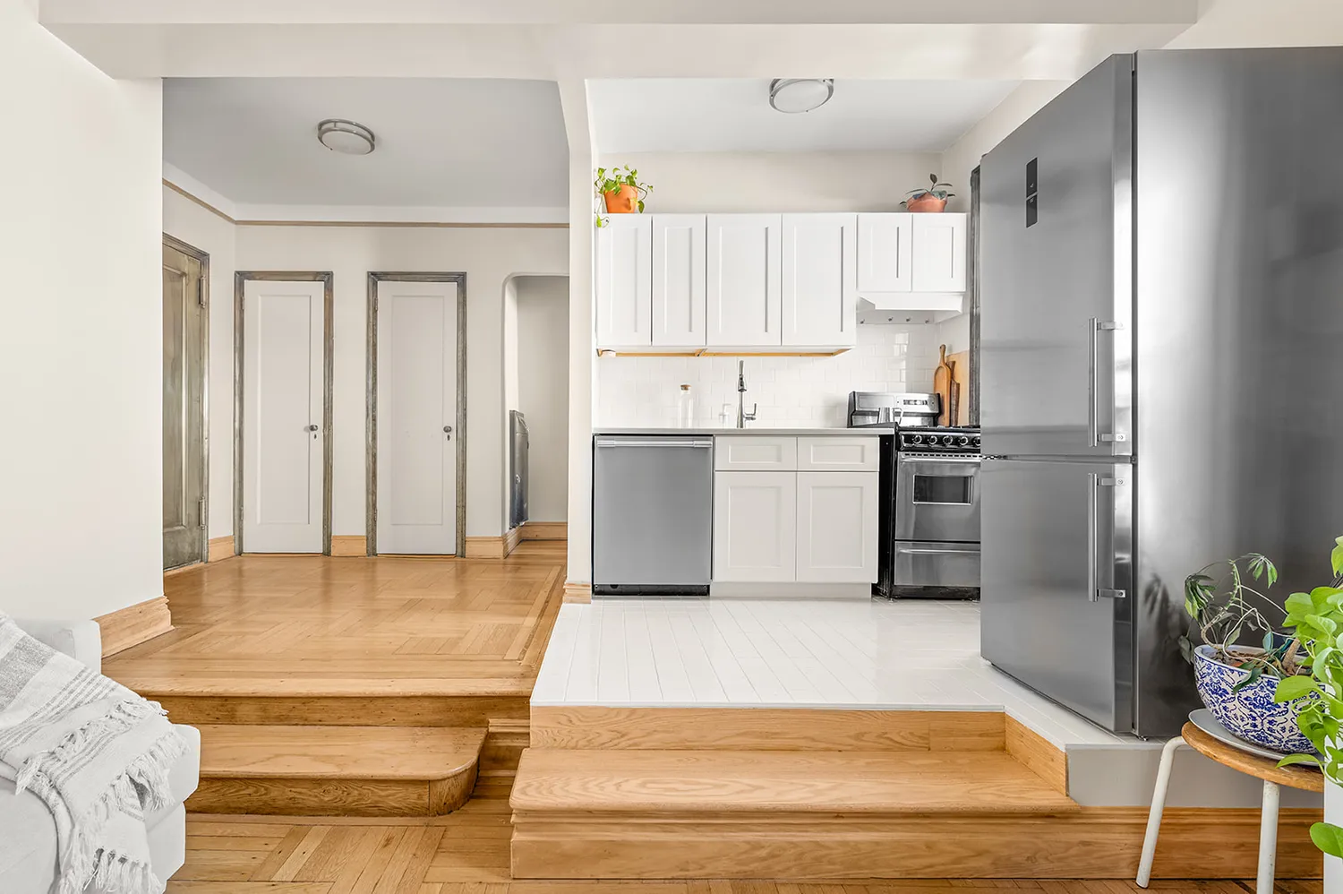 a kitchen with stainless steel appliances kitchen island granite countertop a refrigerator a stove and white cabinets with wooden floor