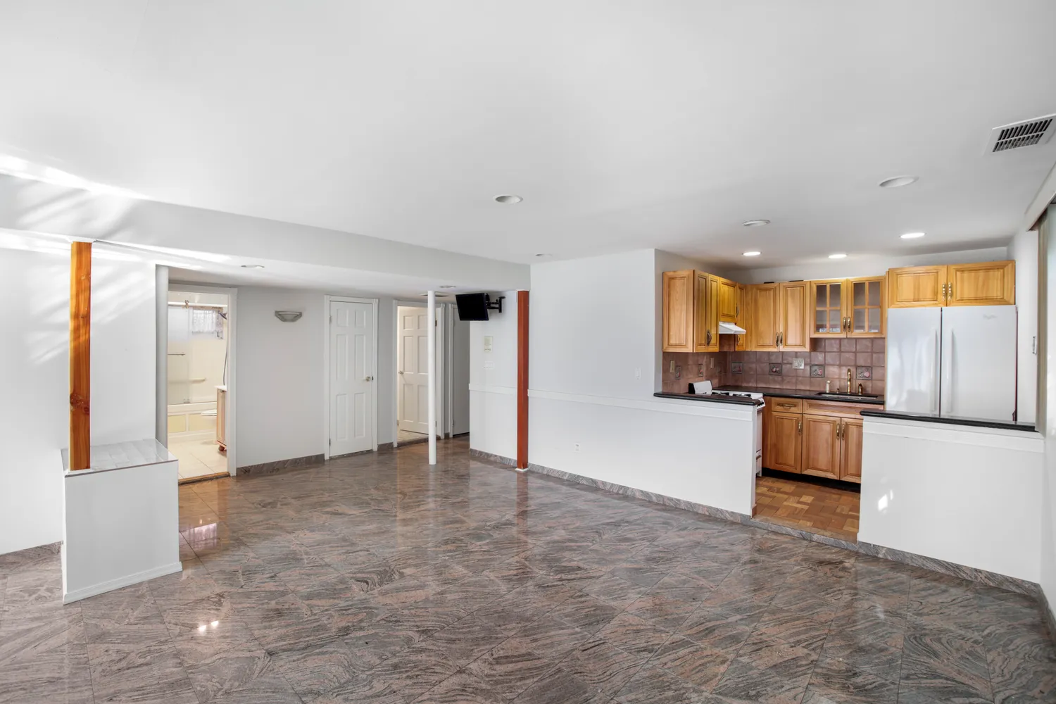 a view of a kitchen with refrigerator and white cabinets