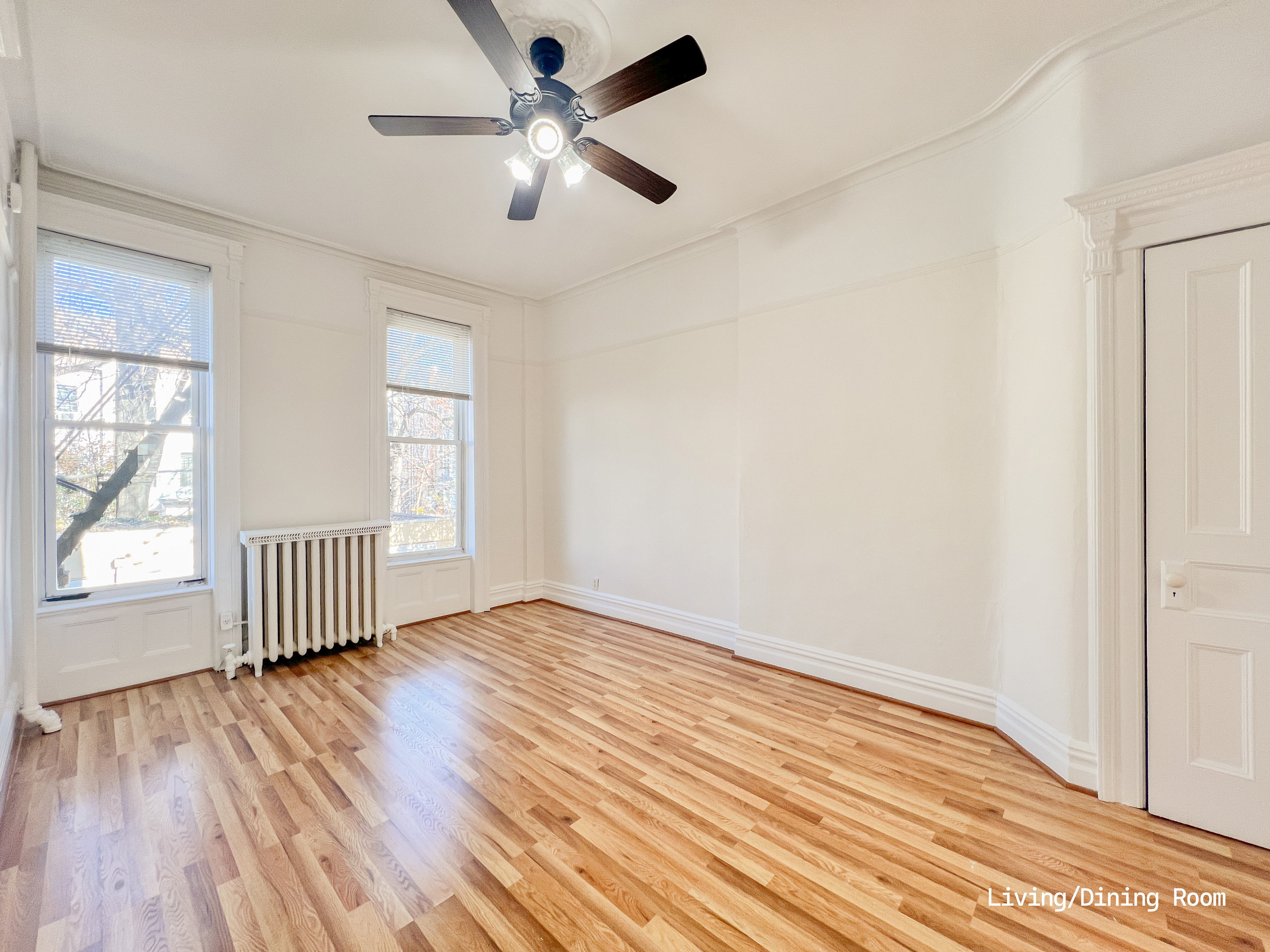 271 71st Street, Unit 2 Brooklyn, NY 11209 - Photo 4 of 10 an empty room with wooden floor chandelier fan and windows