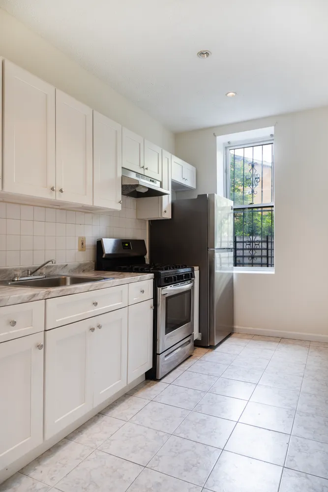 a kitchen with granite countertop a stove a sink and a refrigerator