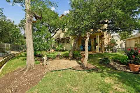 a backyard of a house with plants and large trees