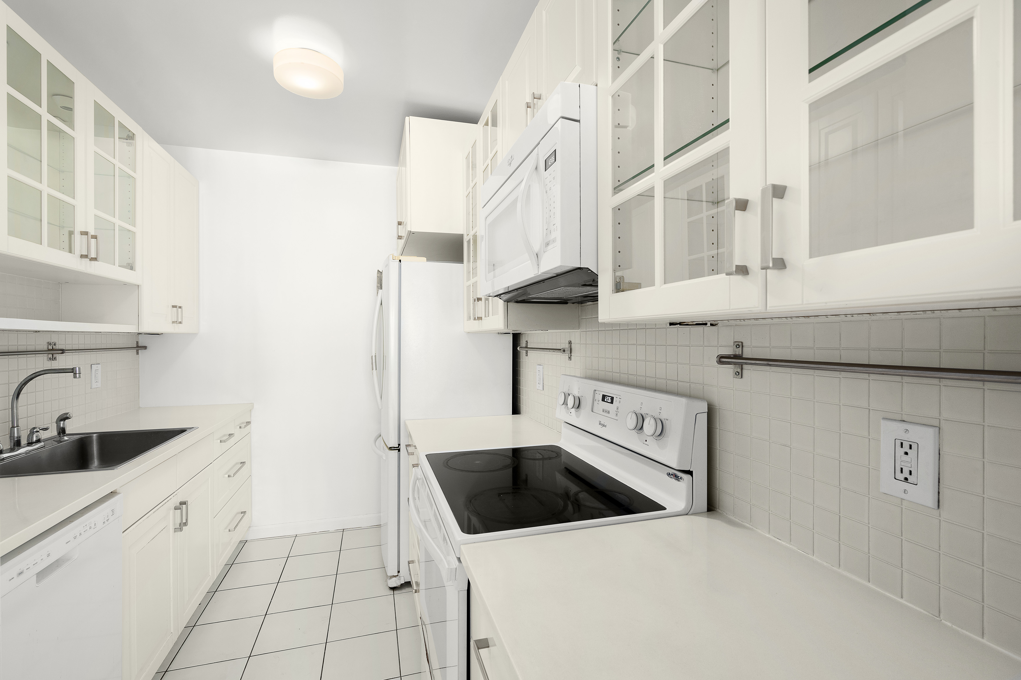240 East 47th Street, Unit 4B Manhattan, NY 10017 - Photo 6 of 25 a kitchen with a sink a stove and cabinets