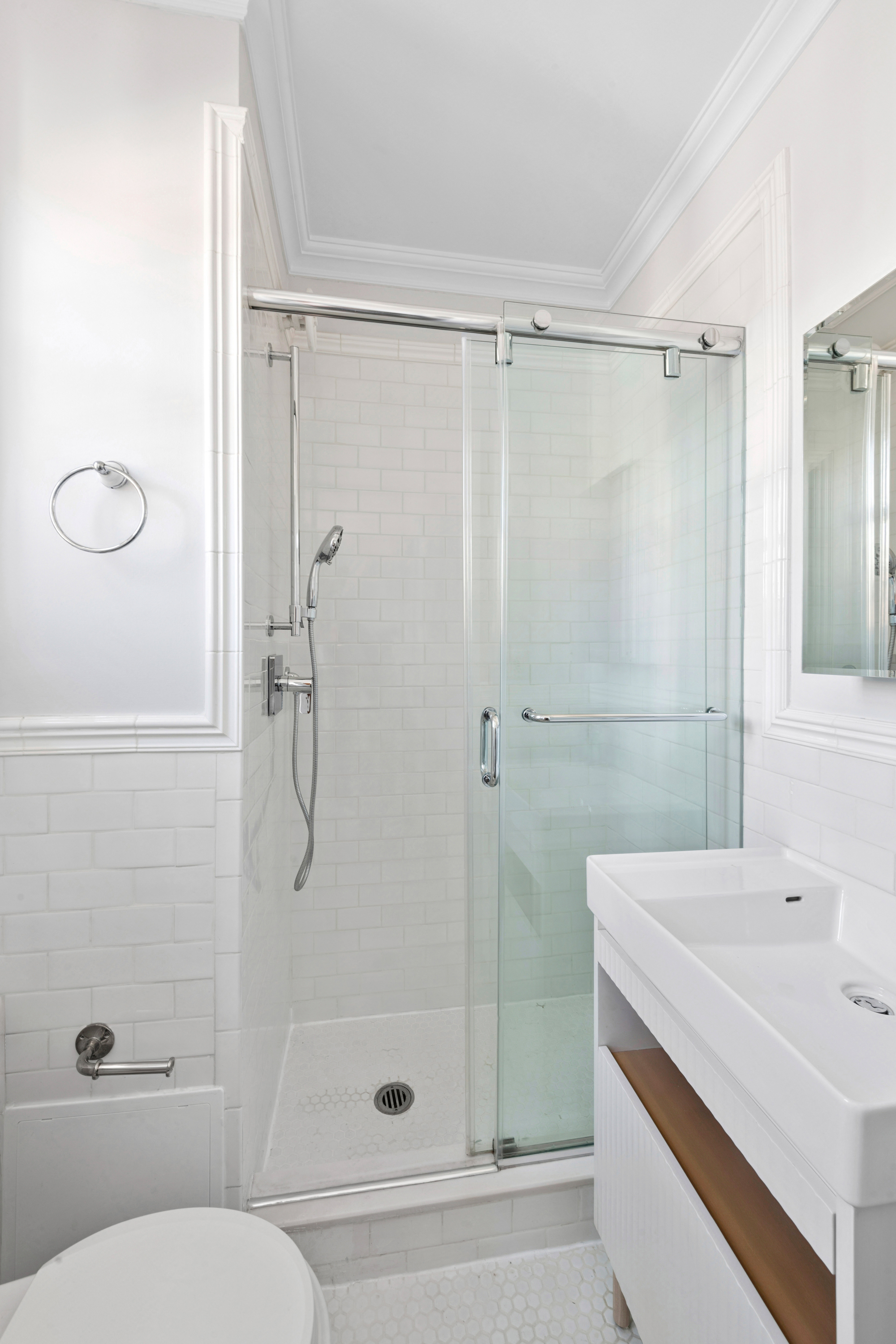 1140 5th Avenue, Unit 14B Manhattan, NY 10128 - Photo 14 of 18 a bathroom with a shower sink vanity and toilet