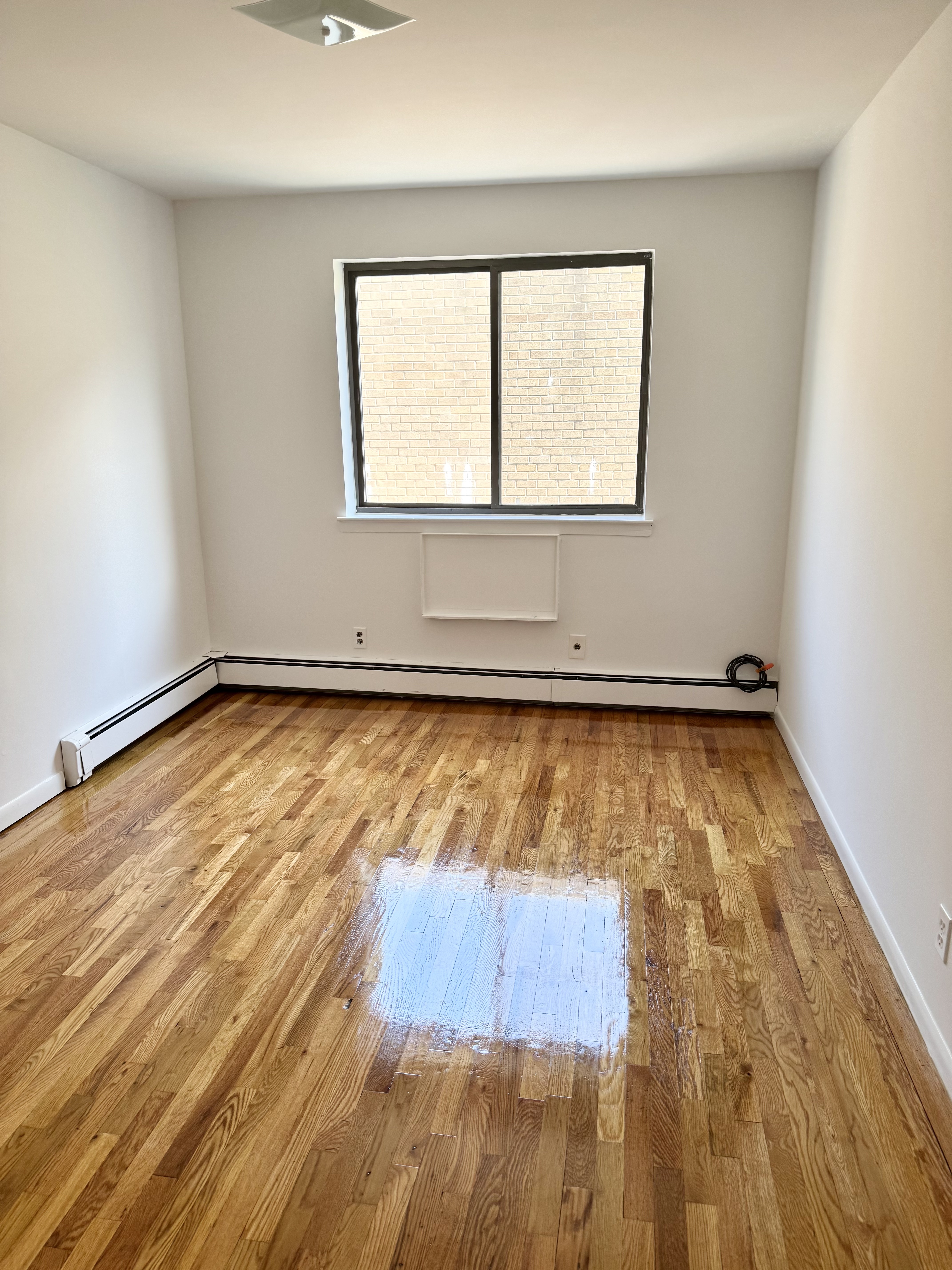 59-15 39th Avenue, Unit 2 Queens, NY 11377 - Photo 11 of 13 a view of a room with wooden floor and a window