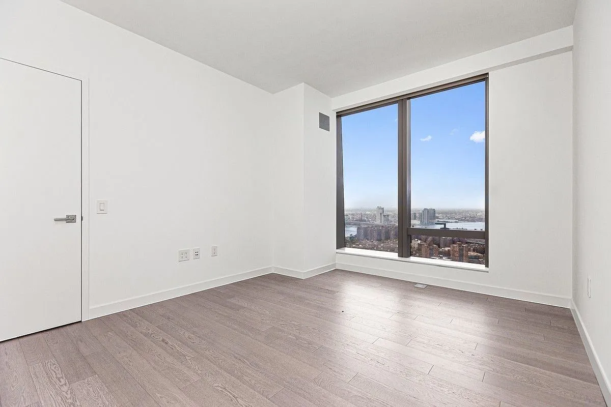 252 South Street, Unit 52J Manhattan, NY 10002 - Photo 3 of 17 an empty room with wooden floor and windows
