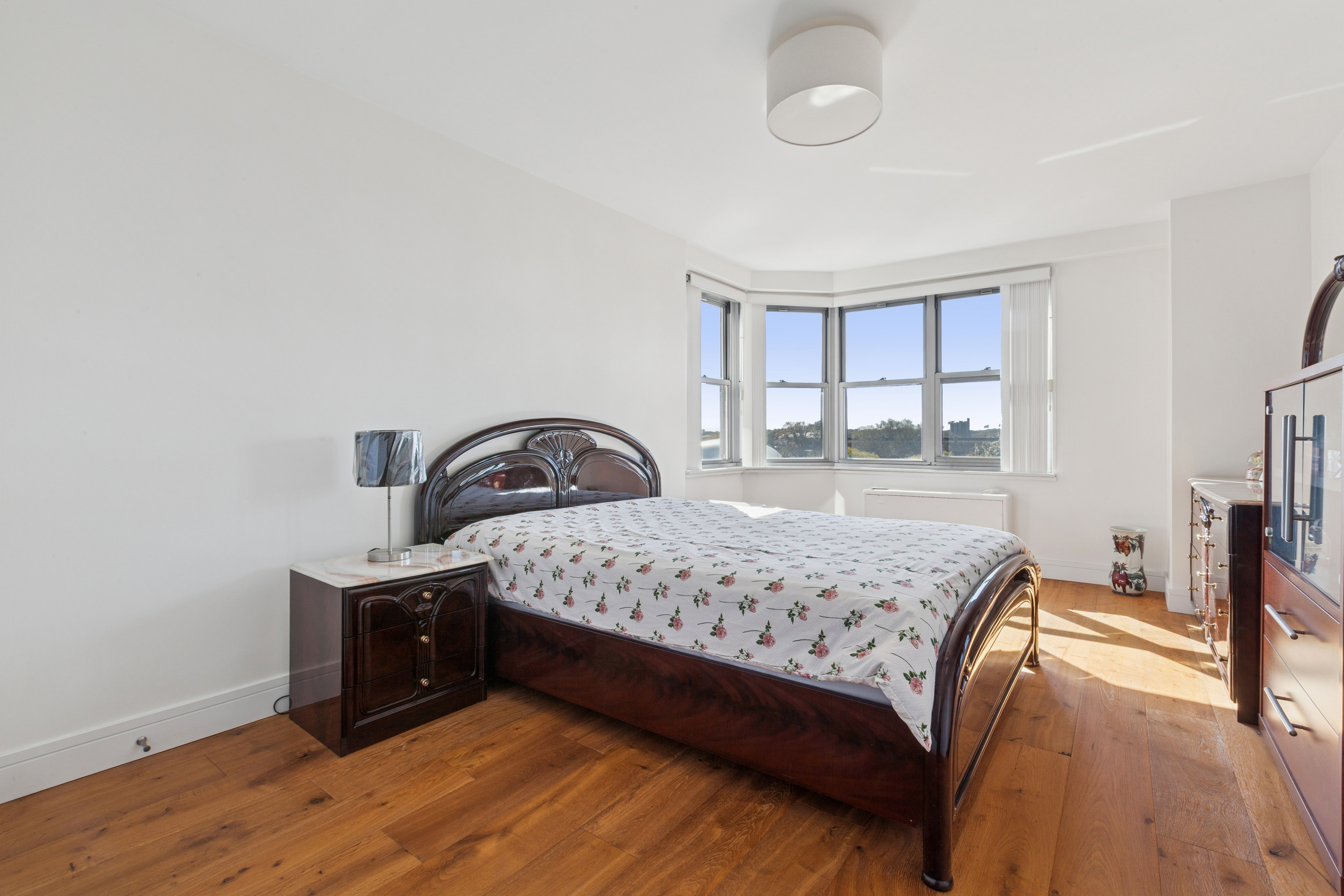 70-25 Yellowstone Boulevard, Unit 8N Queens, NY 11375 - Photo 6 of 19 a bedroom with a bed and a dresser next to a window