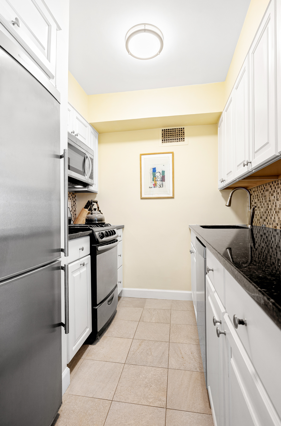 55 East 9th Street, Unit 12H Manhattan, NY 10003 - Photo 4 of 9 a kitchen with stainless steel appliances granite countertop a sink and a stove