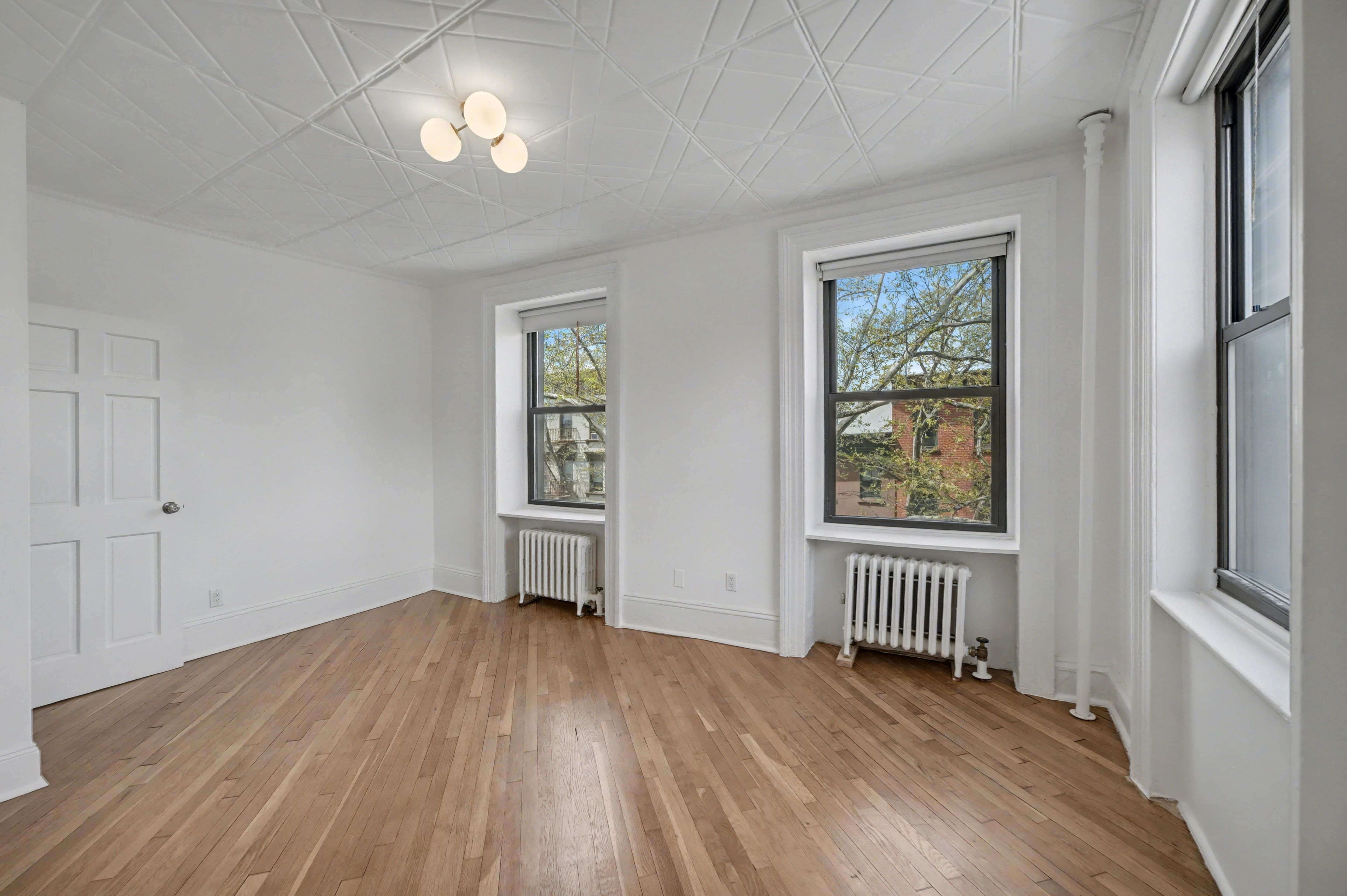 261 Clinton Street, Unit 3 Brooklyn, NY 11201 - Photo 4 of 12 an empty room with wooden floor a ceiling fan and windows