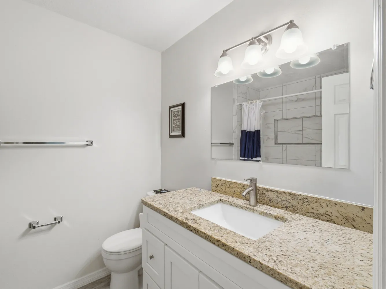 a bathroom with a granite countertop sink a toilet and a mirror