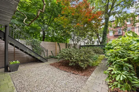 a view of a garden with plants and large trees