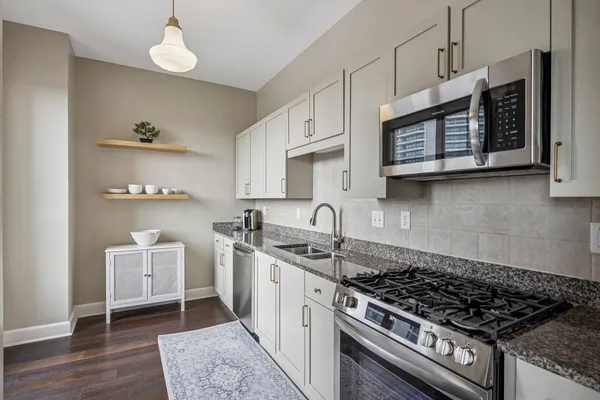 a kitchen with stainless steel appliances granite countertop a stove a sink and a microwave