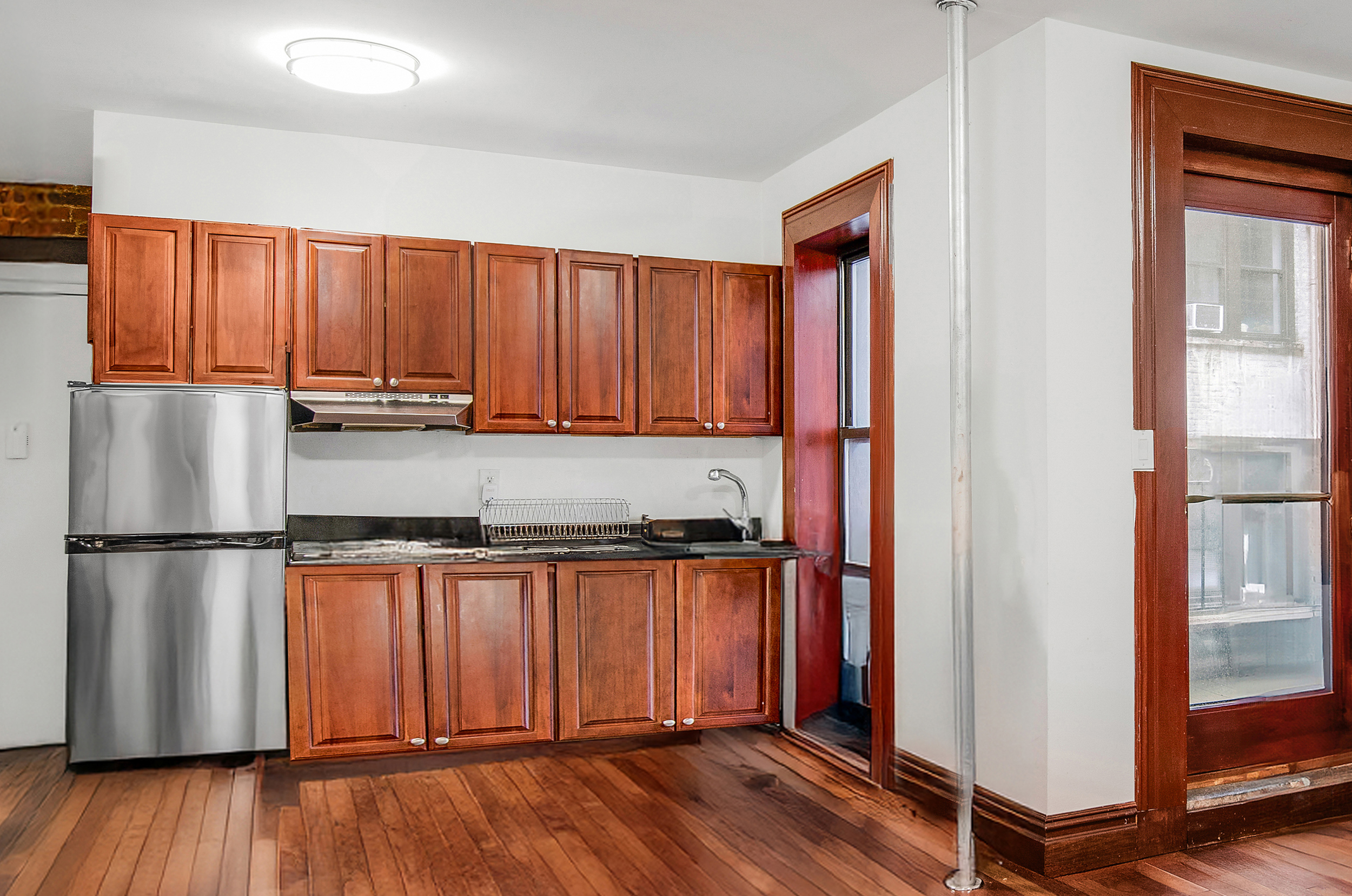 1392 Madison Avenue, Unit 28 Manhattan, NY 10128 - Photo 2 of 10 a kitchen with stainless steel appliances granite countertop a refrigerator a stove a sink and a window