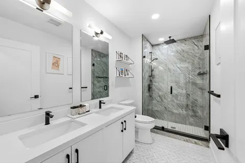 a bathroom with a double vanity sink toilet and shower