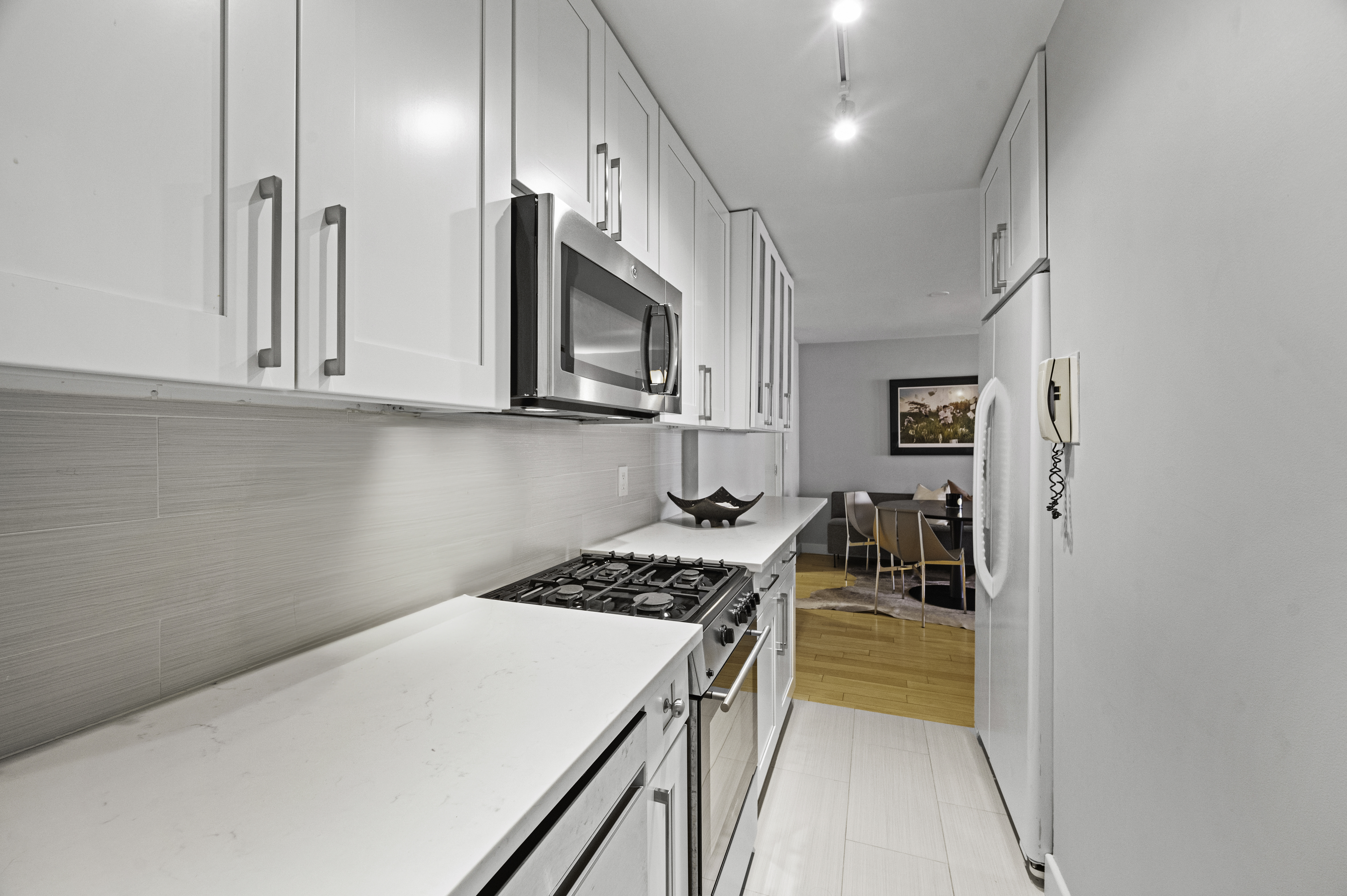 301 East 62nd Street, Unit 7K Manhattan, NY 10065 - Photo 7 of 14 a kitchen with a stove a sink and a microwave