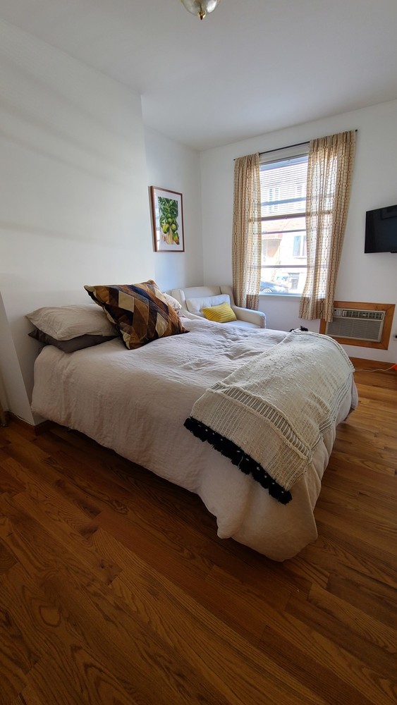 562 Fairview Avenue, Unit 1R Queens, NY 11385 - Photo 7 of 11 a bedroom with a bed and wooden floor