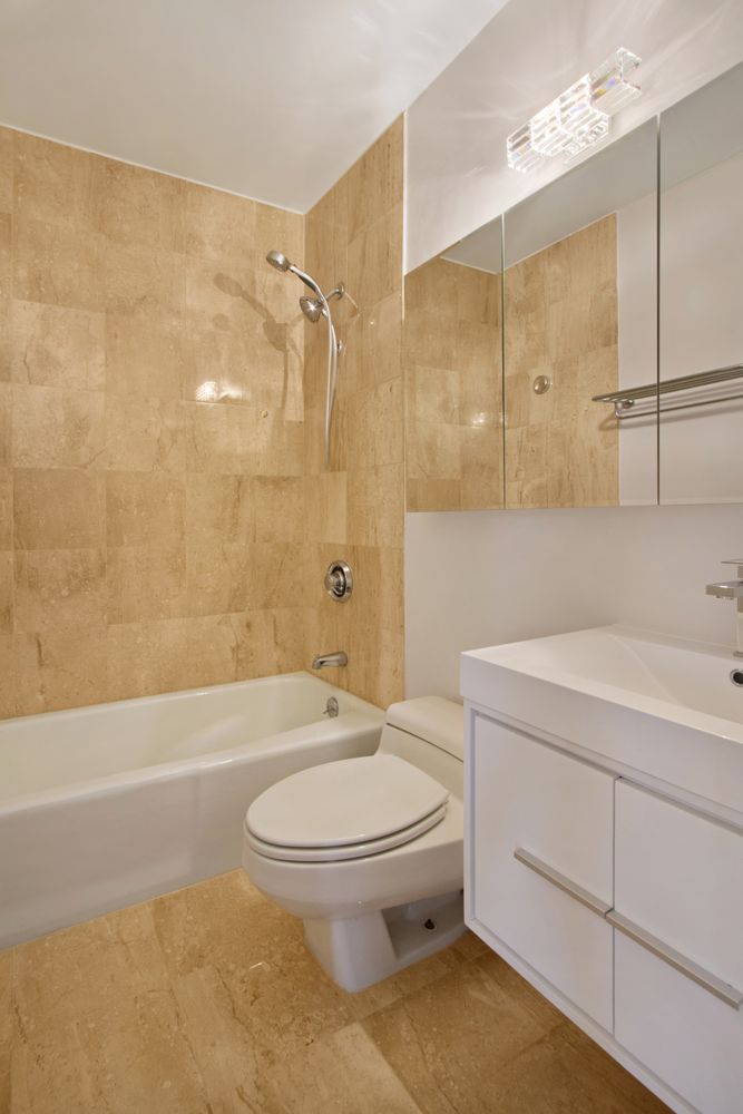 393 West 49th Street, Unit 6G Manhattan, NY 10019 - Photo 6 of 11 a bathroom with a sink a toilet and shower