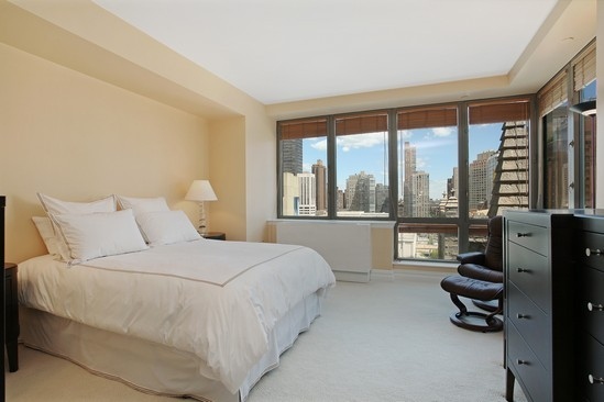 2 Columbus Avenue, Unit 16B Manhattan, NY 10023 - Photo 4 of 5 a bedroom with a bed and a night stand next to a large window