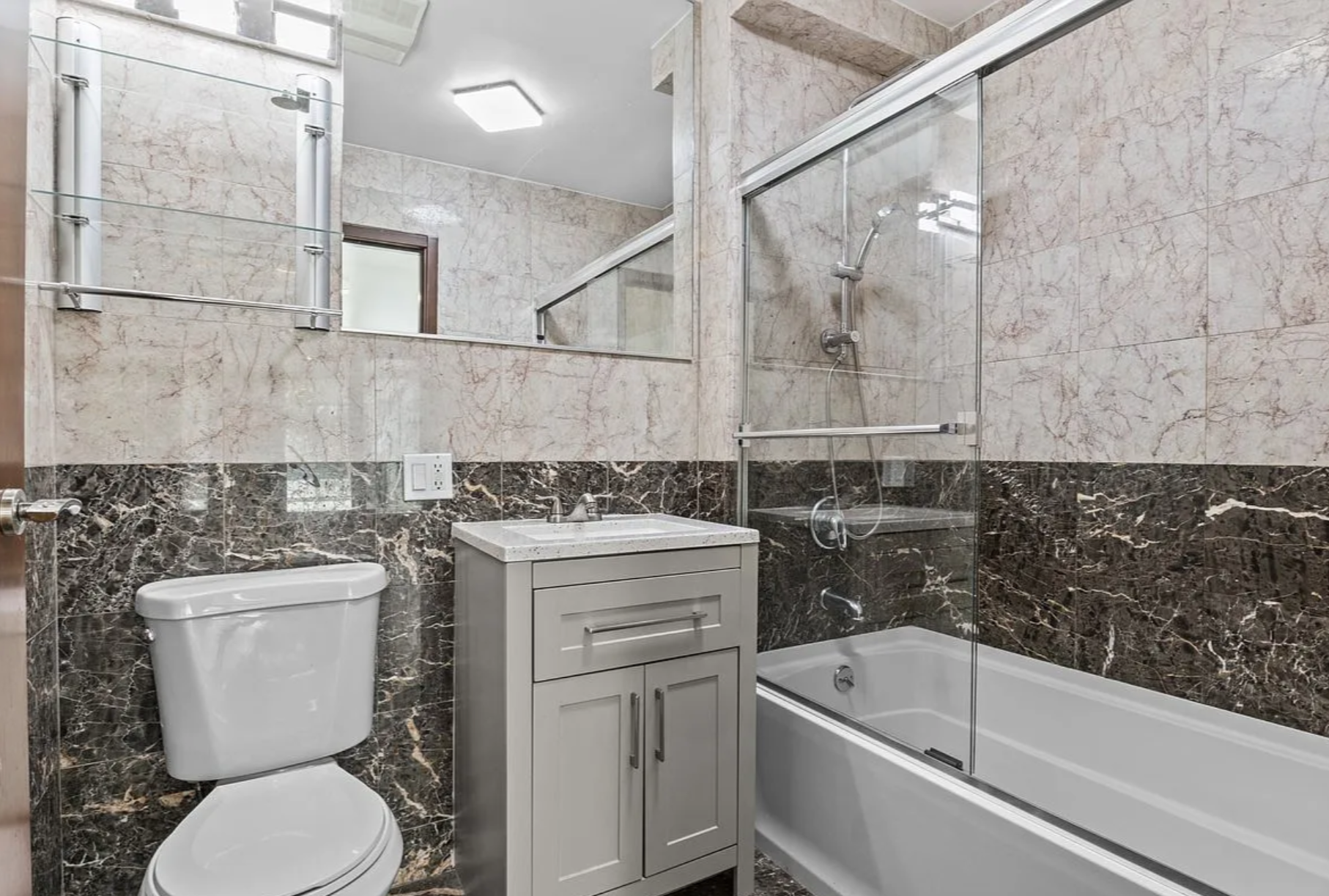 2882 West 15th Street, Unit 2B Brooklyn, NY 11224 - Photo 7 of 13 a bathroom with a granite countertop toilet a sink and bathtub