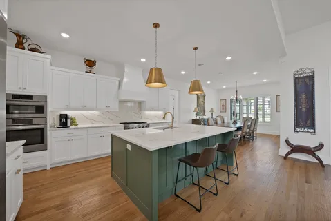 a kitchen with stainless steel appliances a stove a sink a oven a kitchen island with wooden floor and cabinets