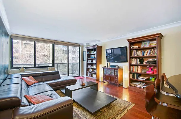 510 East 80th Street, Unit 4D Manhattan, NY 10075 - Photo 11 of 20 a living room with furniture a bookshelf and a large window