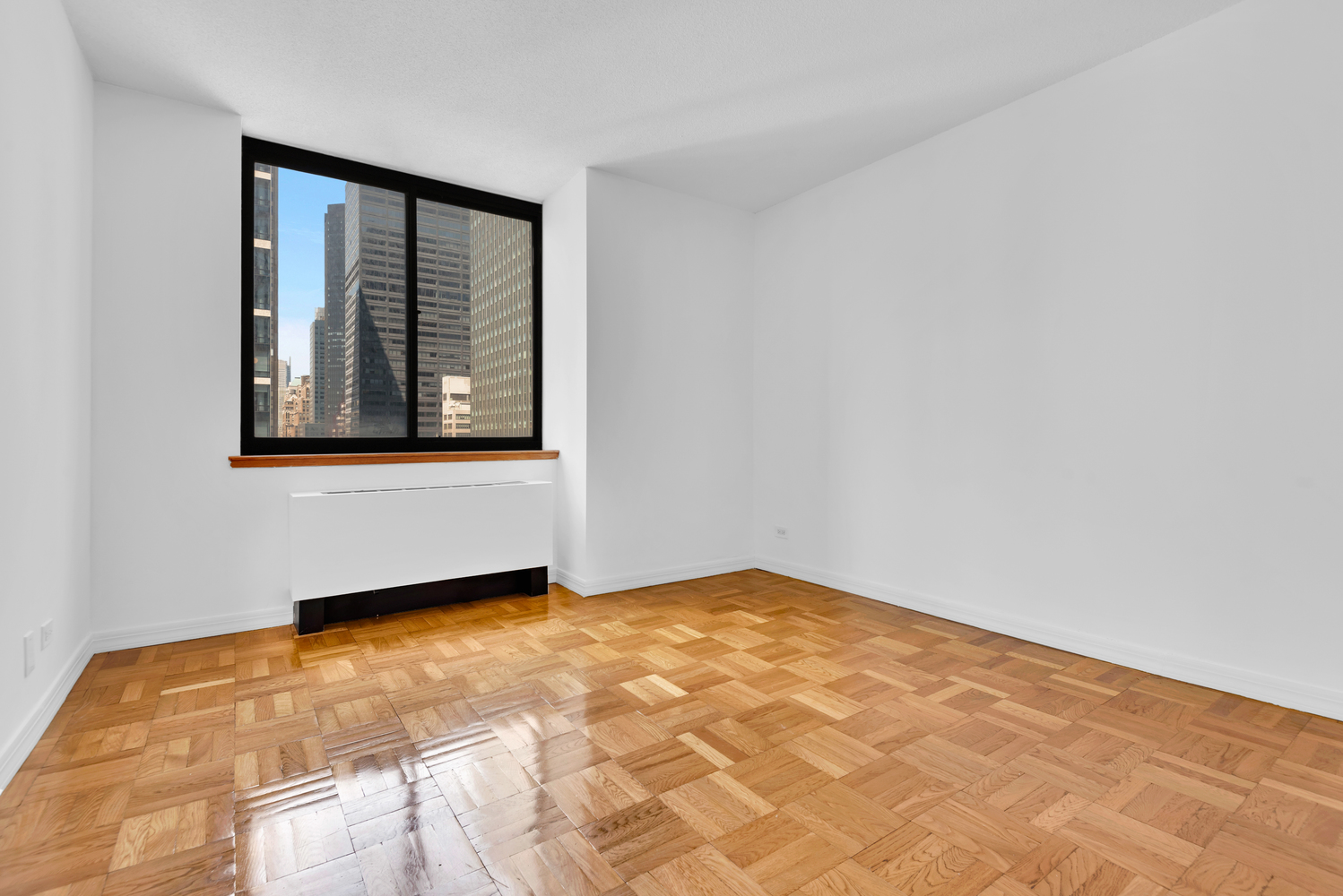 250 East 40th Street, Unit 22B Manhattan, NY 10016 - Photo 8 of 13 a view of an empty room with wooden floor and a window