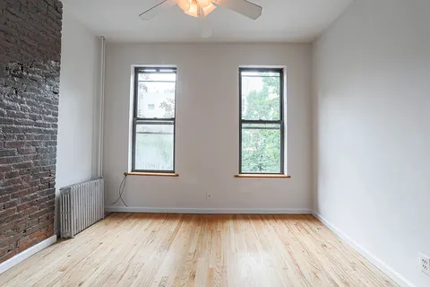 a view of an empty room with wooden floor and window