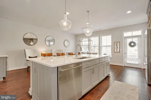 a kitchen with stainless steel appliances granite countertop a stove top oven a sink dishwasher a dining table and chairs with wooden floor