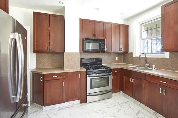 a kitchen with stainless steel appliances granite countertop a refrigerator stove top oven and sink