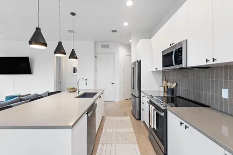 a kitchen with granite countertop a sink stainless steel appliances and white cabinets