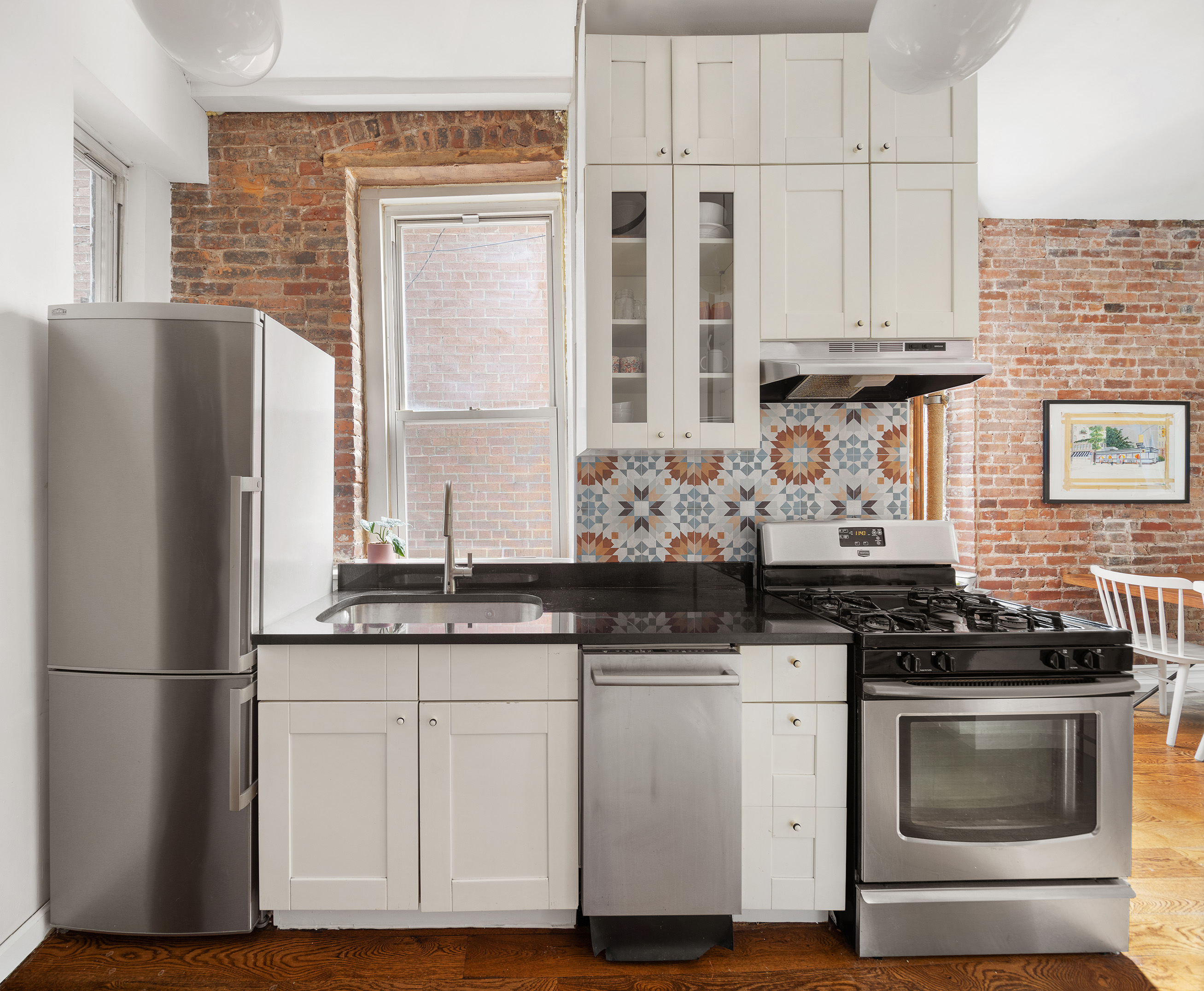 71 East 3rd Street, Unit 4 Manhattan, NY 10003 - Photo 7 of 18 a kitchen with granite countertop white cabinets and stainless steel appliances