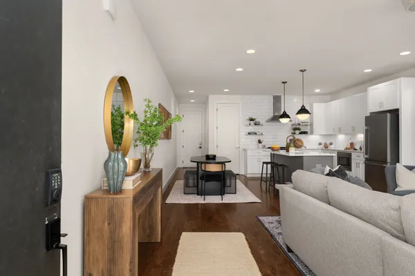 a living room with stainless steel appliances furniture a rug and a view of kitchen