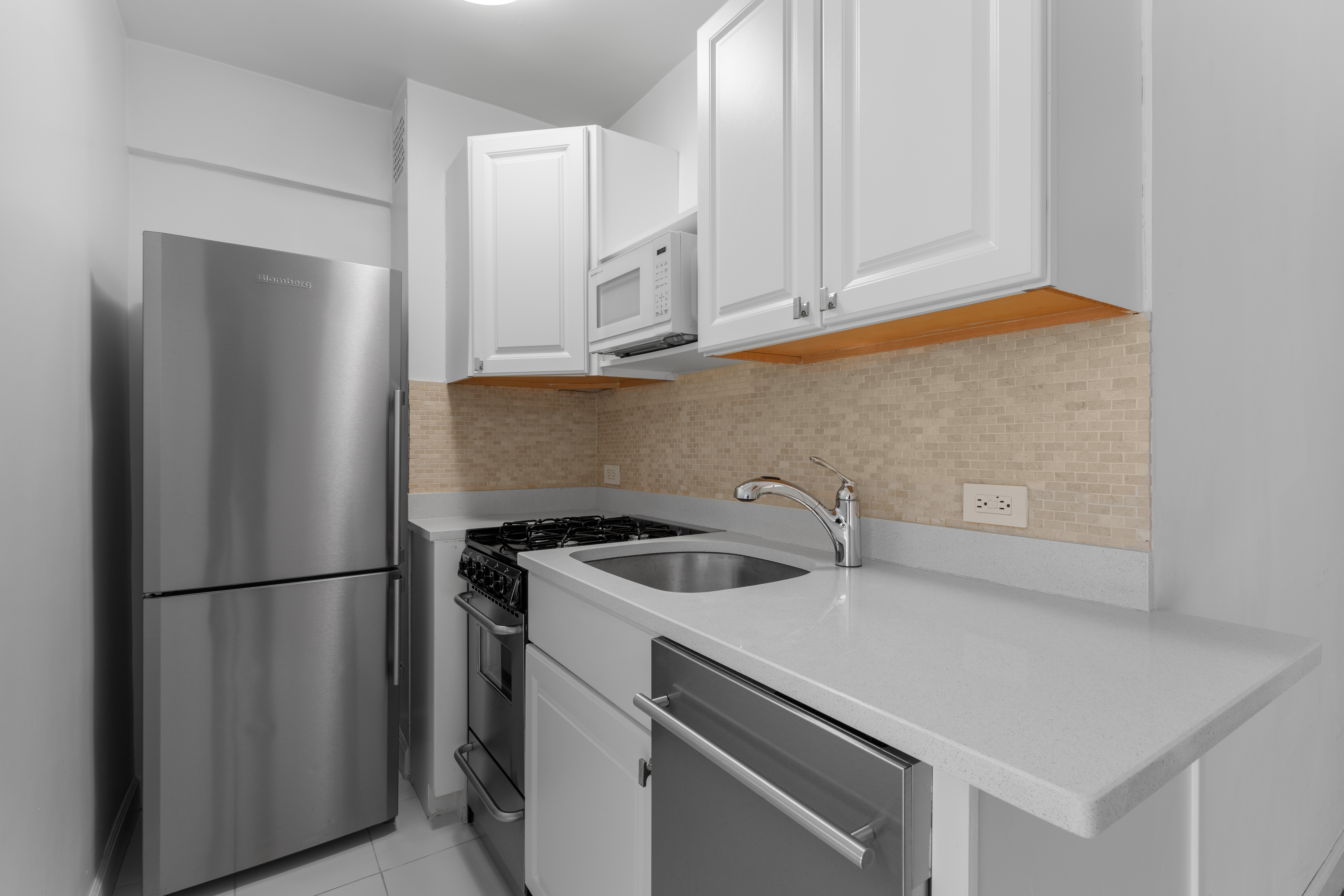 420 East 64th Street, Unit W10K Manhattan, NY 10065 - Photo 5 of 7 a kitchen with stainless steel appliances granite countertop a refrigerator sink and cabinets