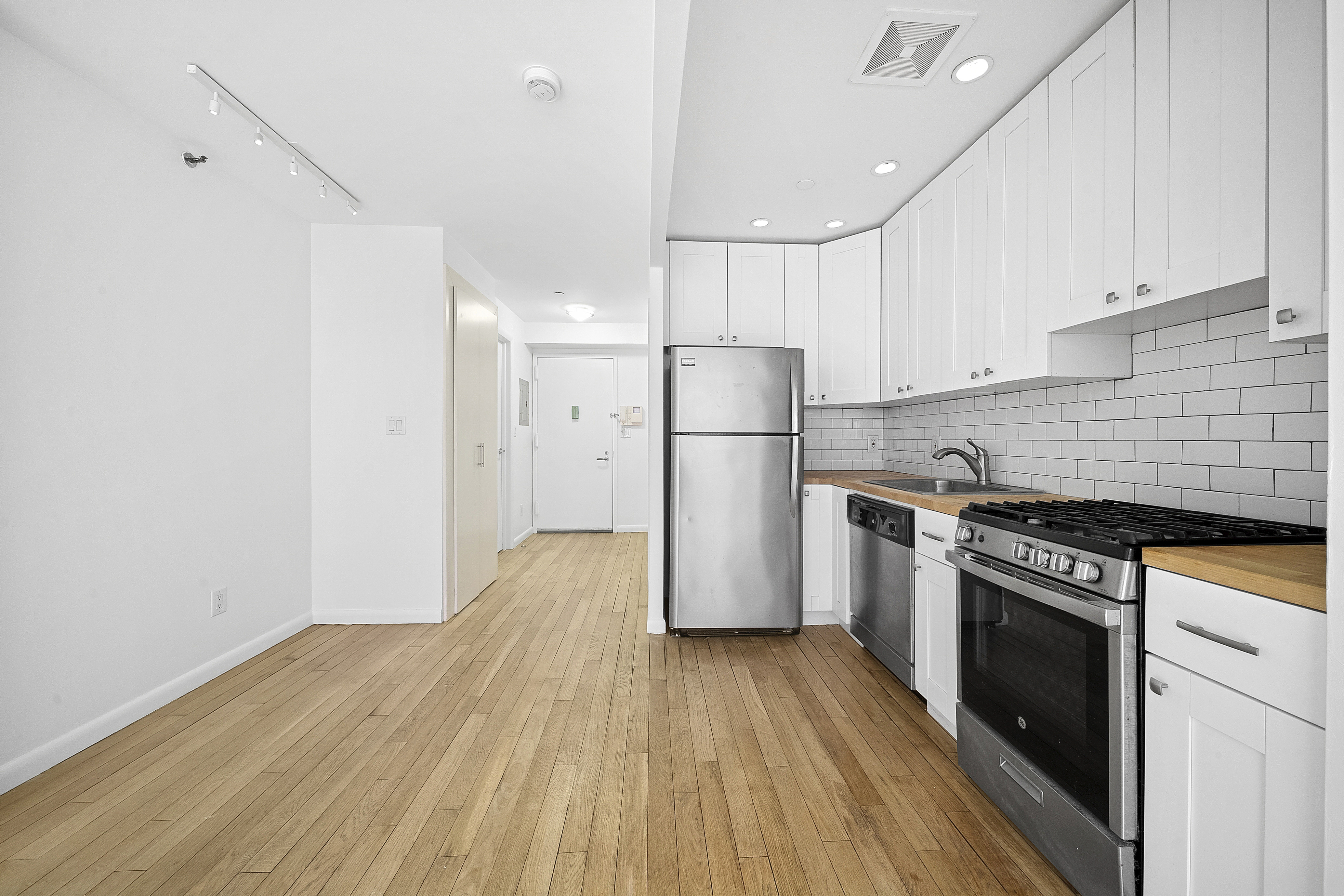 525 East 11th Street, Unit 4D Manhattan, NY 10009 - Photo 3 of 10 a kitchen with a refrigerator a stove top oven and wooden floor