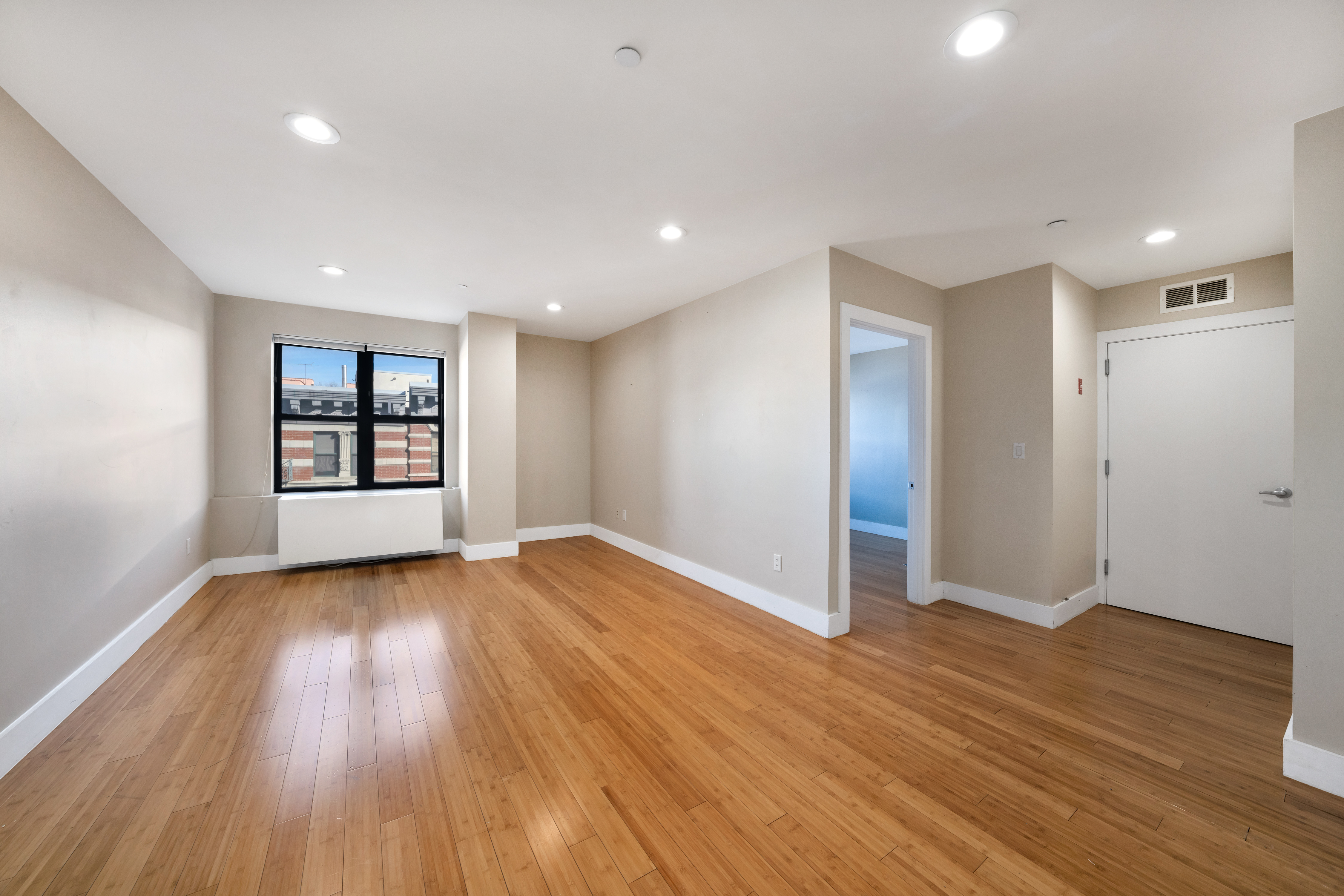 234 West 148th Street, Unit 5D Manhattan, NY 10039 - Photo 3 of 16 a view of an empty room with wooden floor and a window