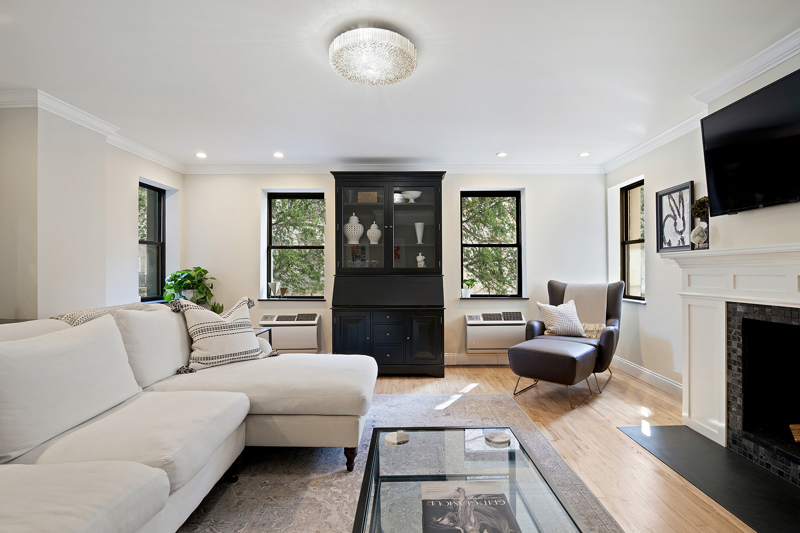 57 East 75th Street, Unit 2F Manhattan, NY 10021 - Photo 3 of 10 a living room with furniture a flat screen tv and a fireplace