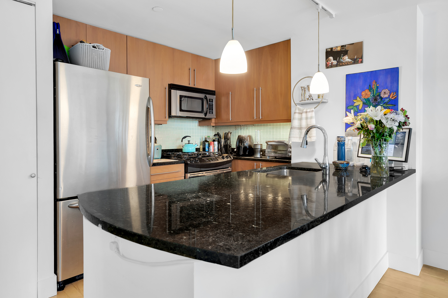 242 East 25th Street, Unit 9B Manhattan, NY 10010 - Photo 2 of 6 a kitchen with stainless steel appliances granite countertop a refrigerator a stove and a sink with wooden floor