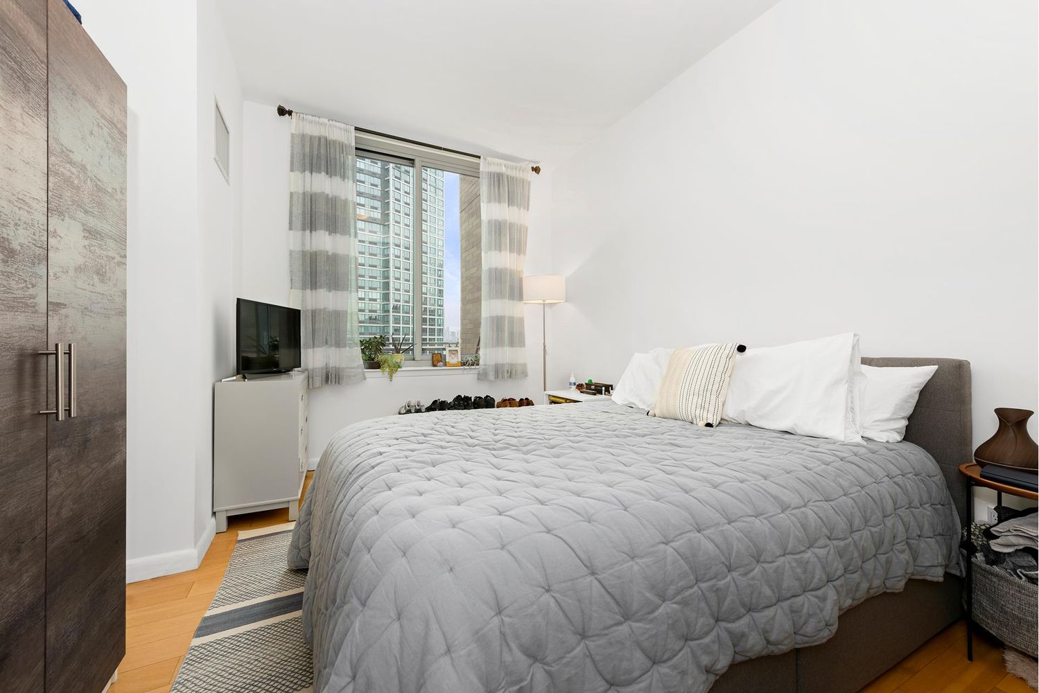 46-30 Center Boulevard, Unit 1106 Queens, NY 11109 - Photo 7 of 9 a bedroom with a bed and flat screen tv