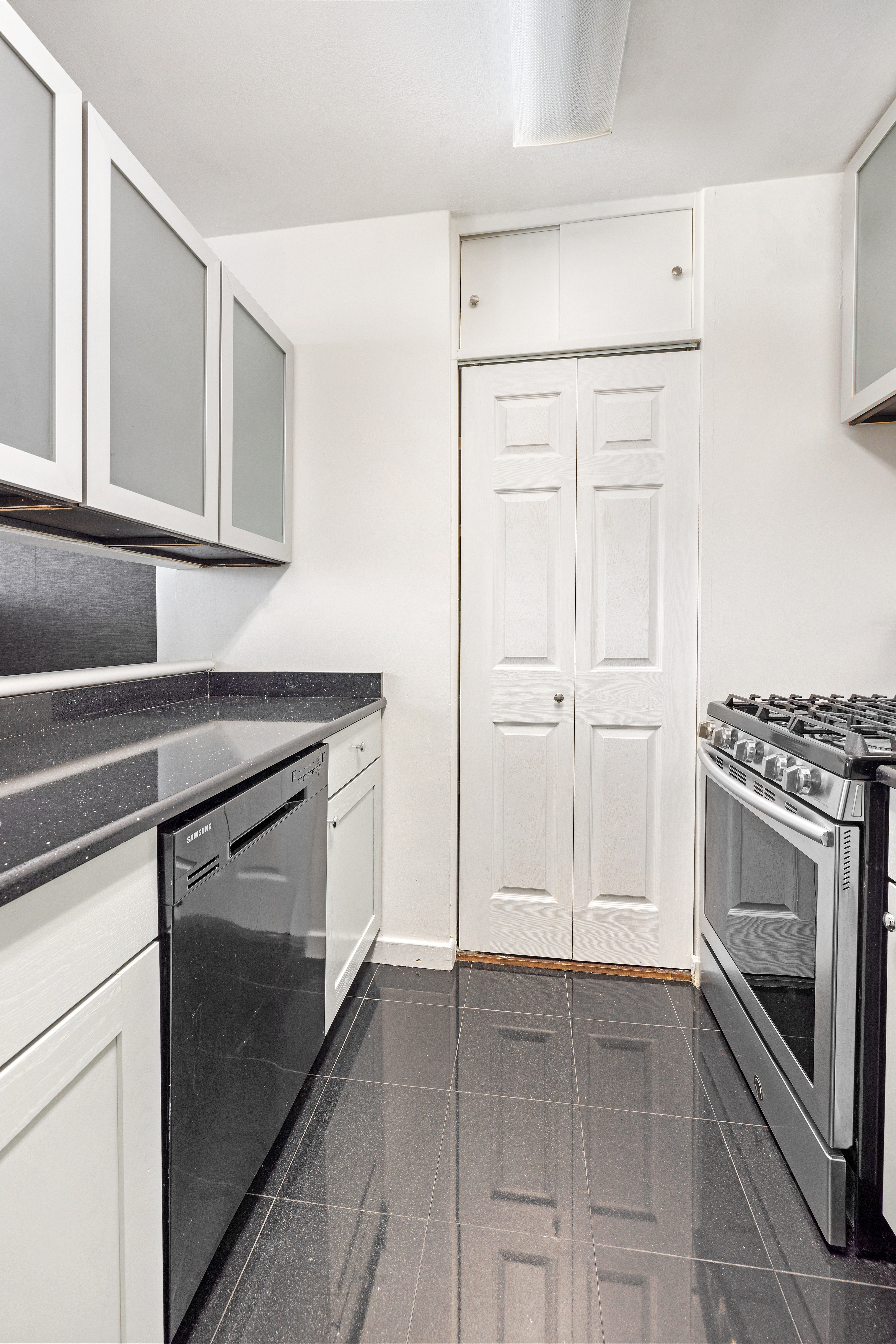 145 East 48th Street, Unit 8D Manhattan, NY 10017 - Photo 3 of 9 a kitchen with white cabinets and stainless steel appliances