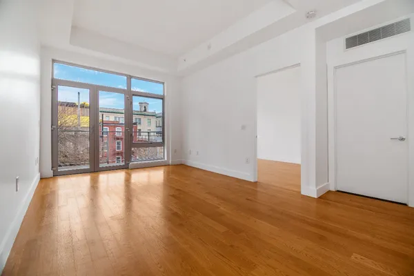 a view of an empty room with wooden floor and a window