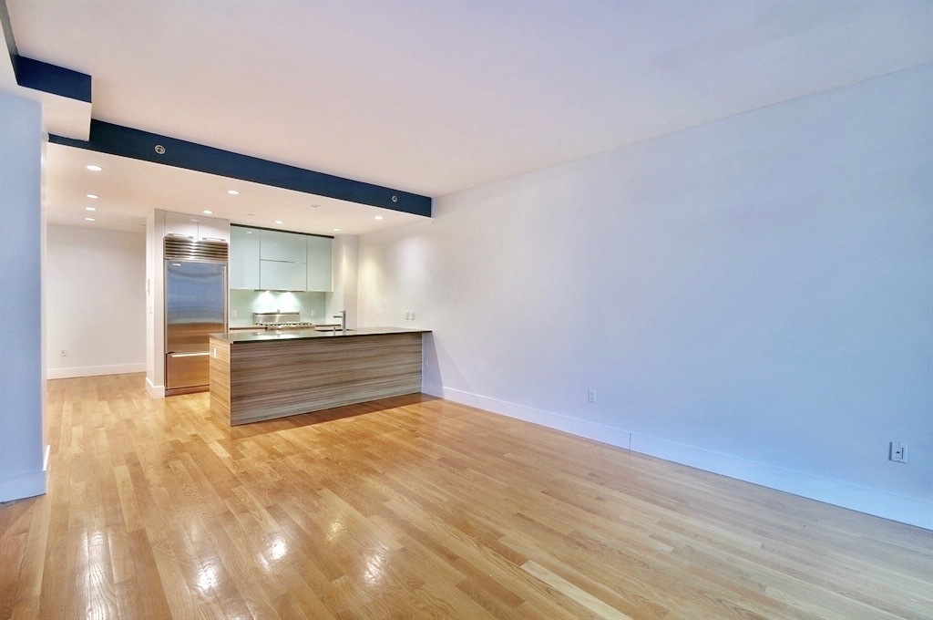 117 West 123rd Street, Unit 4B Manhattan, NY 10027 - Photo 2 of 16 a view of kitchen and empty room with wooden floor